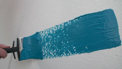 Slow-motion-of-a-hand-painting-a-white-wall-blue-with-a-paint-brush