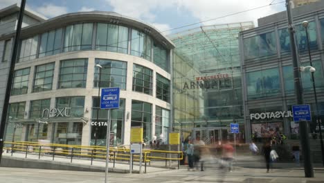 Time-lapse-Del-Centro-Comercial-Arndale-En-La-Ciudad-De-Manchester,-Un-Día-De-Verano-Ajetreado-Con-Gente-Pasando-Y-Líneas-De-Tranvía-En-Uso,-Vías-De-Tren-Pasando-Rápidamente-Y-Nubes-Pasando-Por-Encima-De-Un-Punto-De-Referencia-Turístico-4k-25p