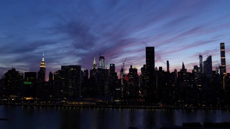 Establishing-shot-of-East-Side-Manhattan,-New-York-City-at-dusk-at-the-shore-of-East-River,-the-Empire-State-Building,-the-Chrysler-building-and-skyscrapers,-filmed-from-Long-Island-City