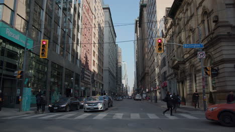 People-crossing-at-Younge-and-Wellting-street-on-a-bright-and-sunny-day-in-Toronto,-Canda