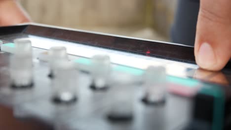 Closeup-of-girl-playing-analogue-electronic-musical-loop-synth-instrument-on-open-air-concert-with-instrument-knobs-in-the-foreground