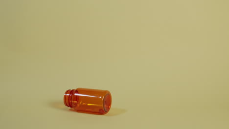 A-pill-bottle-with-one-pill-tumbles-into-frame-left-and-rolls-around