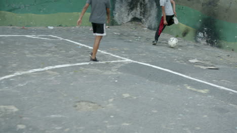 Hand-held-shot-of-South-African-boys-playing-street-football-in-a-township-playground-Salamander-Park-in-Hangberg-residential-area