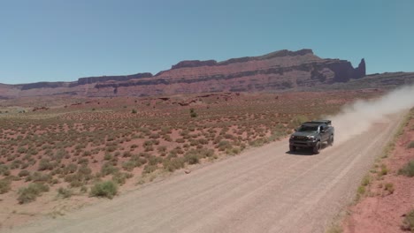 Seguimiento-Aéreo:-Un-Camión-Con-Una-Carpa-En-El-Techo-Avanza-Por-Una-Polvorienta-Carretera-Del-Desierto