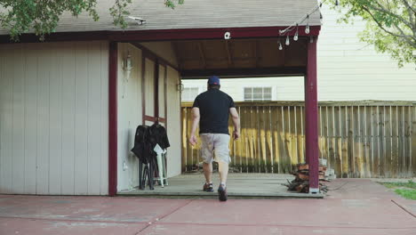 Wide-shot-of-a-man-walking-towards-the-backyard-tool-shed