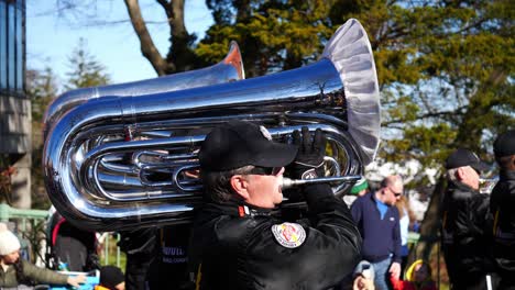 Tubaspieler-In-Schwarzer-Jacke-Und-Schwarzer-Baseballkappe-Spielt-Tuba,-Während-Er-Während-Der-Thanksgiving-Parade-2019-In-Plymouth,-Massachusetts,-Die-Straße-Entlang-Geht