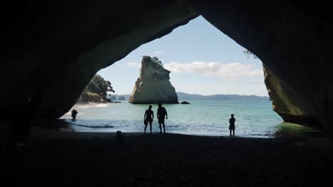 Silhouette-tourists-enjoy-dark-cool-air-inside-large-black-sea-cave