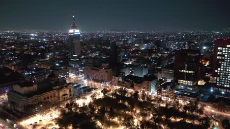 Volando-Sobre-El-Palacio-De-Bellas-Artes-Y-El-Parque-Central-De-La-Alameda-Hacia-La-Torre-Latinoamericana-En-La-Ciudad-De-México-Por-La-Noche