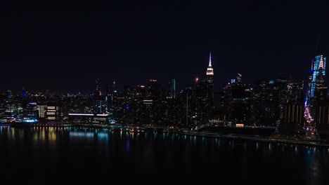 La-Luna-Se-Esconde-Y-Sale-Detrás-De-La-Silueta-De-Los-Rascacielos,-Vista-Aérea-De-La-Ciudad-De-Nueva-York-Por-La-Noche,-Con-Autos-Y-Luces-Moviéndose-En-Las-Calles