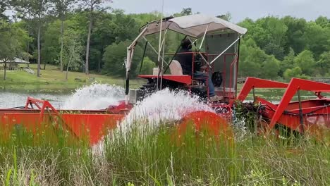 Amphibientraktor-Fährt-Vorbei,-Während-Er-Den-örtlichen-Teich-Von-überwucherter-Vegetation-Ausbaggert