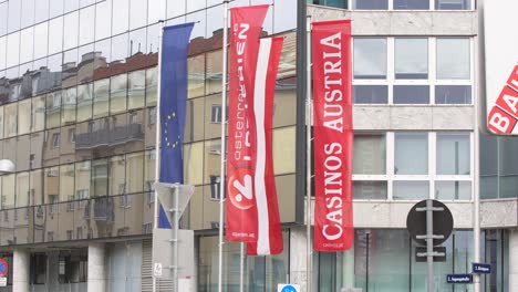 Casinos-Austria-Hauptsitz-Flaggen-Mit-Logo-Glasgebäude-Reflexion