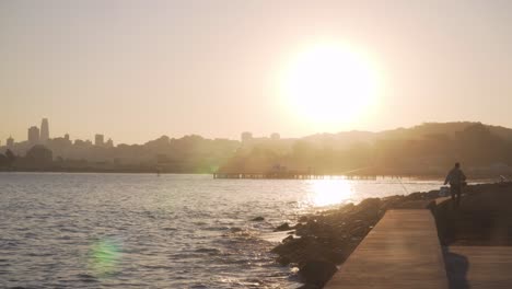 Silhouette-Eines-Fischers-Am-Ufer-An-Einem-Sonnigen,-Ruhigen-Morgen