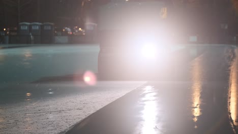 Handheld-shot-of-zamboni-smoothing-outdoor-ice-rink-at-night