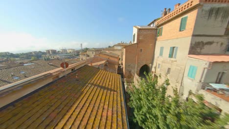 Close-flight-between-the-roofs-of-the-medieval-village-Sinalunga-in-Tuscany,-Italy