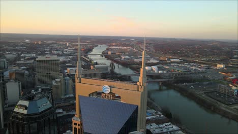 Full-aerial-orbit-of-the-AT-and-T-building,-revealing-the-skyline-of-downtown-Nashville-during-sunset