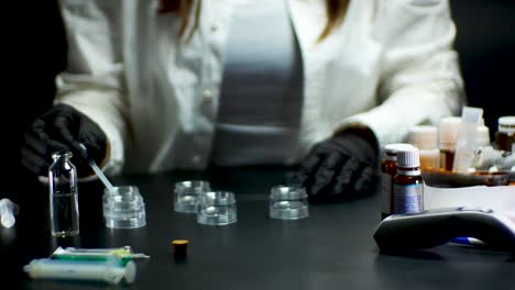 Laboratory-assistant-in-black-gloves-testing-vaccine-with-pipette-and-medicaments-on-the-side-of-the-table