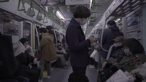 Pasajeros-Con-Mascarillas-En-El-Interior-De-Un-Tren-En-Movimiento-En-Tokio,-Japón