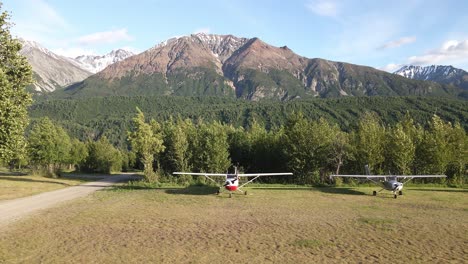 Aerial-footage-truck-shot-along-a-row-of-airplanes-parked-along-a-grass-airstrip-in-the-Talkeetna-Range-of-Alaska