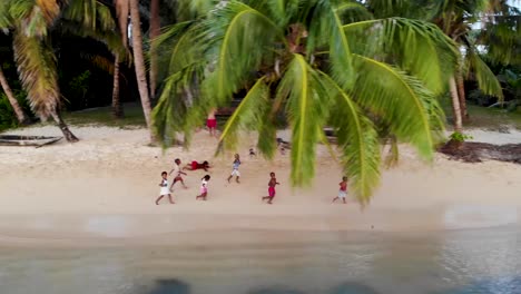 Children-running-along-beach-chasing-drone