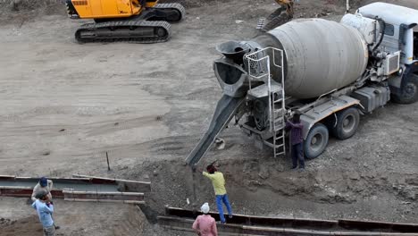 Primer-Plano-Del-Hormigón-Que-Fluye-Y-Se-Vierte-Desde-Un-Camión-Hormigonera-Que-Vierte-Hormigón-Líquido-En-Una-Carretera-En-Obras-En-El-Sitio-De-Construcción,-Un-Camión-Hormigonera-Vierte-Hormigón-En-Construcción-De-Una-Carretera