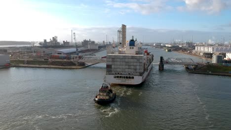 Container-ship-passing-raised-bridge-with-tugboat-assistance-in-Antwerp