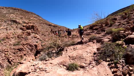 Hiking-up-a-rocky-cliff-trail-over-a-mountain-with-a-small-group-of-tourists-on-a-hot-humid-day