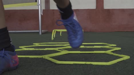 Jugador-De-Fútbol-En-Una-Velocidad-Hexagonal-Y-Anillos-De-Escalera-De-Entrenamiento-De-Agilidad-En-El-Campo