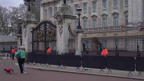 Buckingham-Palace-attendants-and-mourners-walking-in-front-of-palace-gates,-the-day-after-death-of-Prince-Philip,-Duke-of-Edinburgh,-Saturday-April-10th,-2021---London-UK