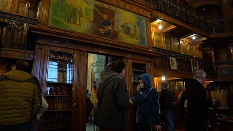 Pan-to-the-right-of-a-group-of-people-on-tour-at-the-Jose-Toribio-Medina-Hall,-National-Library-of-Chile,-Santiago,-Chile