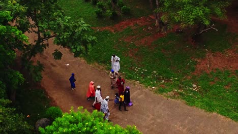 Vista-Aérea-De-Una-Familia-Con-Ropa-Tradicional-Africana-Caminando-Por-El-Sendero-De-Un-Hermoso-Parque-Verde-En-Abuja,-Nigeria.