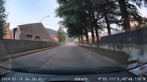 POV-car-drives-quickly-through-town-and-crosses-bridge,-dash-cam-footage