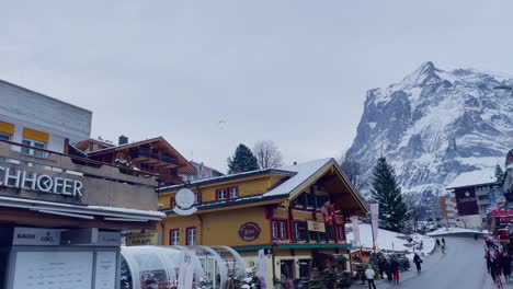 Geschäftiges-Bergstädtchen-Grindelwald-In-Der-Schweiz-In-Der-Wintersaison,-Touristen-Filmen-Berge