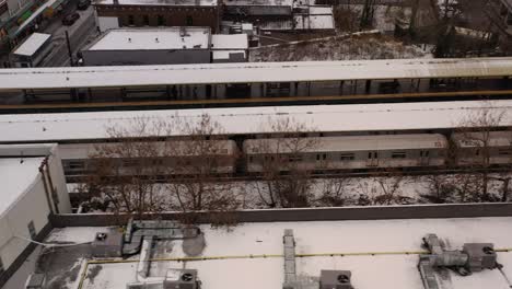 An-aerial-view-of-a-subway-train-leaving-the-station-on-a-snowy-day