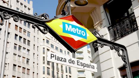 Plaza-de-España-metro-station-sign-with-spanish-flag-and-Gran-Via-street-behind-in-Madrid