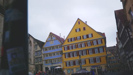 Ciudad-Histórica-De-Tubinga,-Alemania-|-Mujer-Caminando-Por-Teléfono-Cerca-De-Edificios-Coloridos