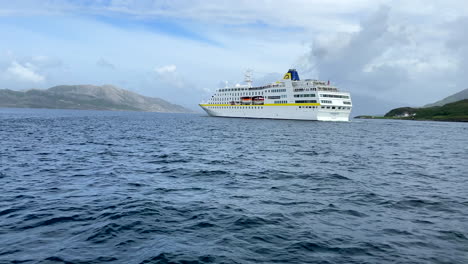 Toma-Panorámica-Con-Cámara-En-Mano-Del-Crucero-Hamburg-Pasando-Por-El-Círculo-Polar-ártico-Con-Un-Cielo-Parcialmente-Nublado-En-Helgeland,-Noruega