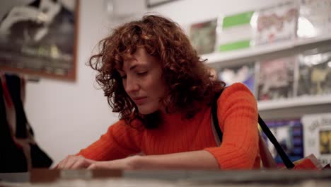 Attractive-Curly-Woman-Browsing-Vinyl-Records-In-Music-Disc-Shop