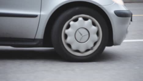 Close-up-view-of-silver-car-wheel-passing-by-on-the-asphalt-road