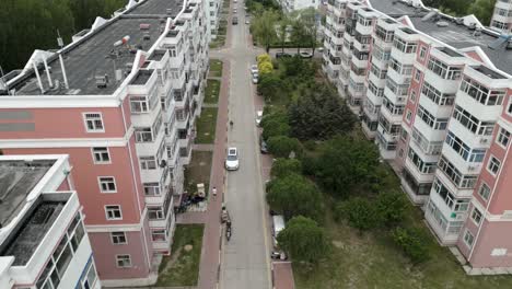 Drone-footage-of-a-quiet-street-in-Daqing,-between-two-residential-buildings-with-cars-parked-along-the-road