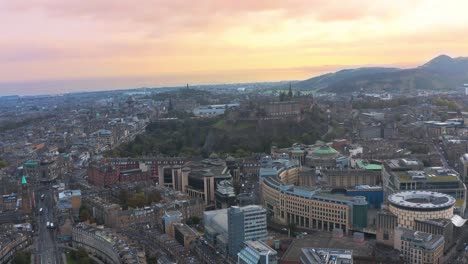 Sunset-drone-view-of-the-city-of-Edinburgh,-stunning-colored-sky-in-the-horizon,-copy-space