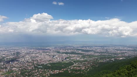 Vista-Aérea-De-La-Ciudad-De-Sofía,-Bulgaria,-Desde-Lo-Alto-De-La-Montaña-Vitosha-En-Un-Hermoso-Día-Con-Nubes-Blancas-Y-Esponjosas