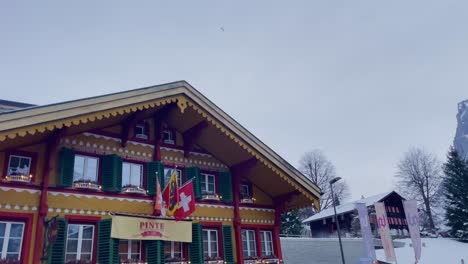 Geschäftiges-Bergstädtchen-Grindelwald-In-Der-Schweiz-In-Der-Wintersaison,-Auto-Fährt-Am-Hotel-Vorbei