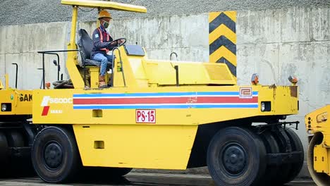 West-Java-Indonesia---February-11,-2002-:-Worker-driving-a-Compactor---Pneumatic-Tired-Roller-during-asphalt-paving