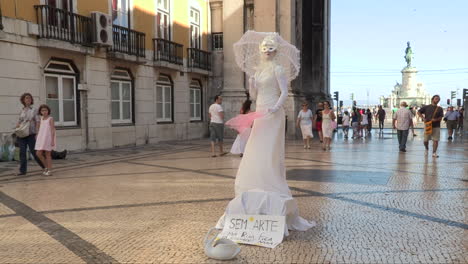 Performance-of-a-Statue-Woman-on-Rua-Augusta,-next-to-the-Arc-de-Triumph,-with-the-monument-and-equestrian-statue-of-King-José-I