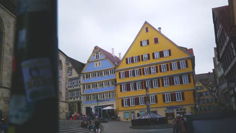 Ciudad-Histórica-De-Tubinga,-Alemania-|-Señora-Mayor-Caminando-Cerca-De-Edificios-Coloridos