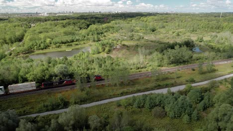 Toma-Aérea-De-Seguimiento-Del-Tren-De-Carga-De-CN-Rail-Que-Transporta-Suministros-De-Carga-Vitales-A-Través-Del-Desierto-Canadiense