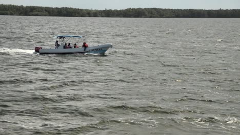 Kleines-Motorboot,-Das-Auf-Dem-Meer-Segelt,-Mit-Menschen,-Die-Schwimmwesten-Tragen