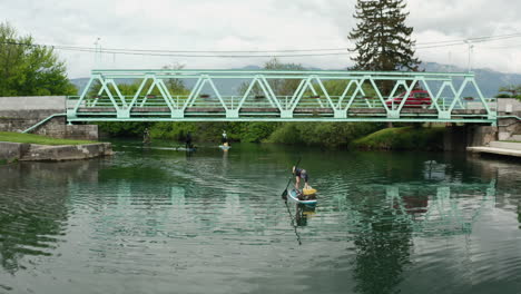 Paddleboarding-under-a-beautiful-iron-green-bridge-in-Vipava,-Slovenia