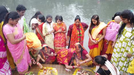 View-of-the-Indian-people-doing-rituals-during-Hindu-wedding-with-fruits,-fire,-flowers-in-front-of-ganga-river-water