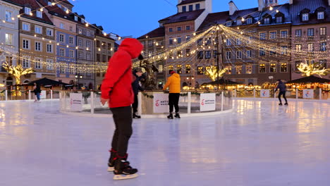 Varsovia,-Polonia---Diciembre-De-2021:-La-Gente-Se-Divierte-En-La-Pista-De-Hielo-Por-La-Noche-Durante-La-Temporada-Navideña-En-La-Plaza-Del-Mercado-Del-Casco-Antiguo-De-La-Capital